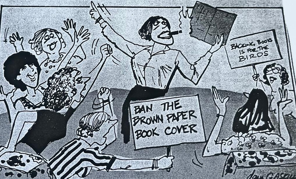 Cartoon accompanying the column: BAN THE BROWN PAPER BOOK COVER, on a placard held up in a hall of cheering mothers, with a second reading BACKING BOOKS IS FOR THE BIRDS and a woman standing over them with a cigar in her teeth and an exercise book held aloft.